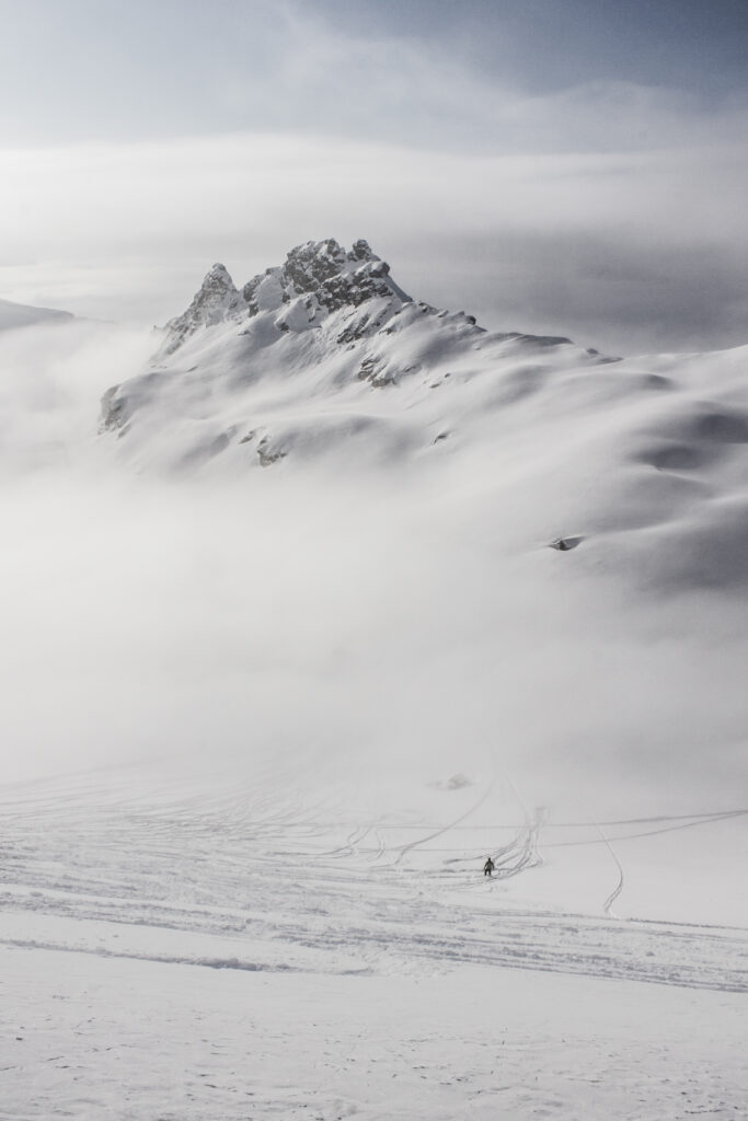 Snow-covered mountain peak in gentle mist surrounded by crisp white snow and soft clouds Wallpaper