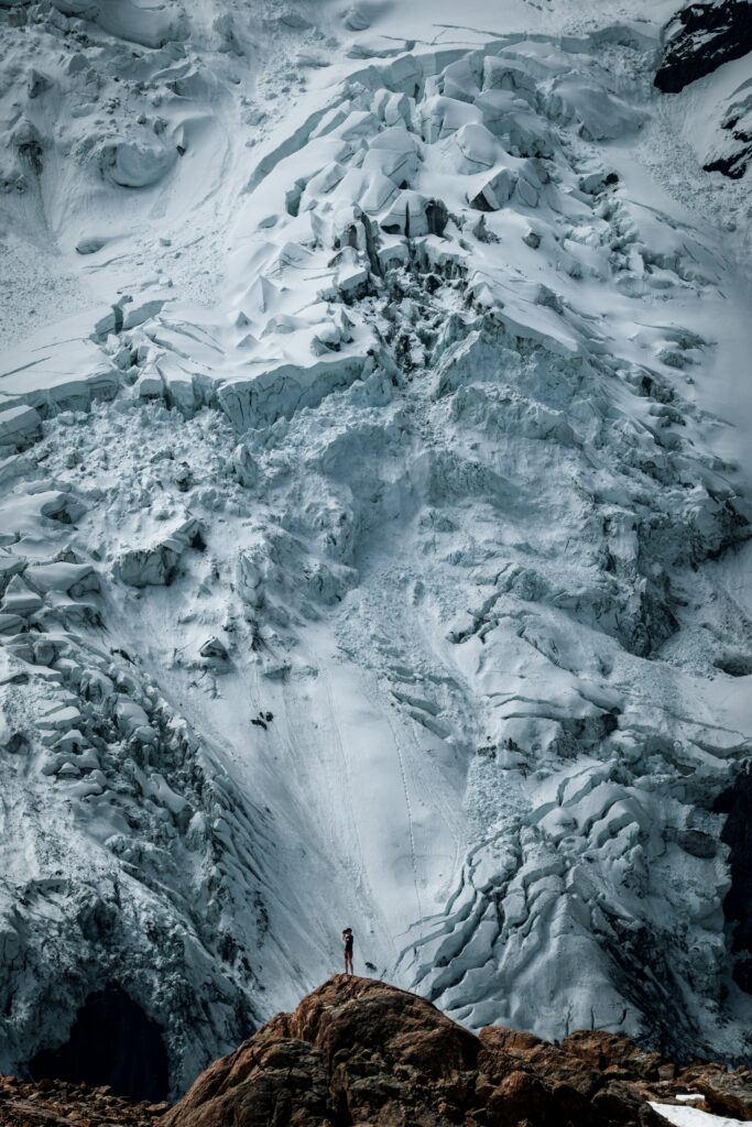 Snow-covered towering mountains with rugged icy textures and sandy rocky foreground wallpaper background