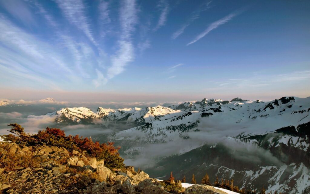Snow covered majestic mountain tops with fresh clouds and rugged stones under blue sky wallpaper