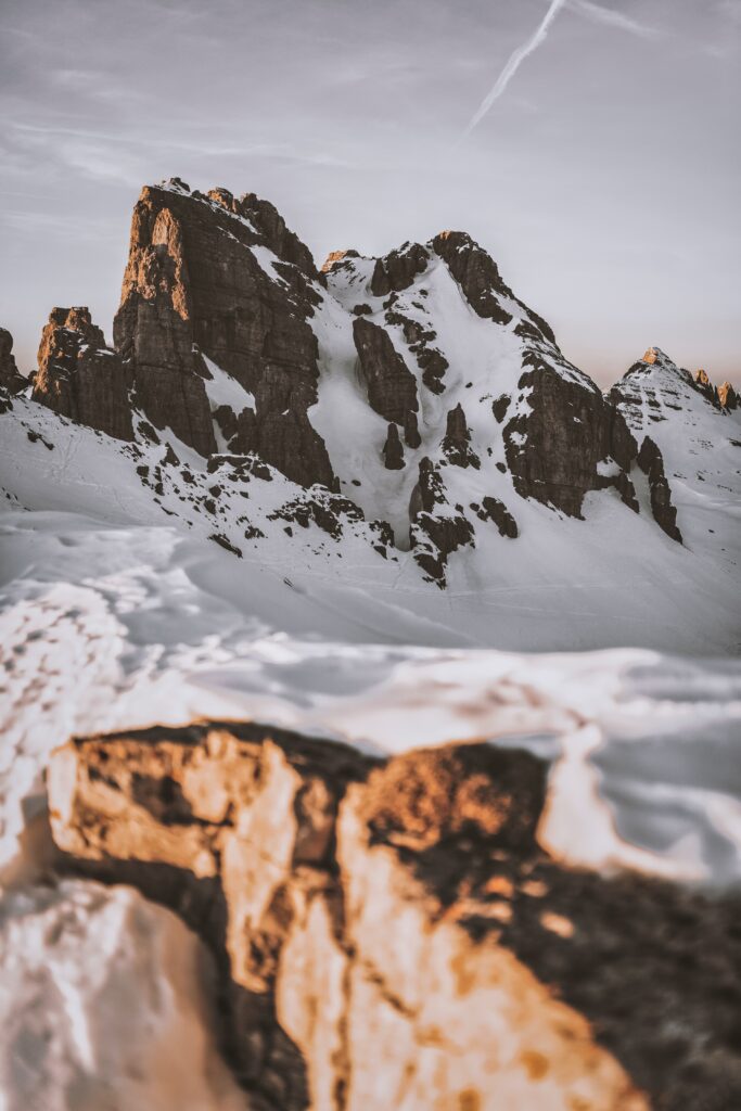 Snow-covered rugged rock formations bathed in warm sunlight showcasing textured mountain relief Wallpaper