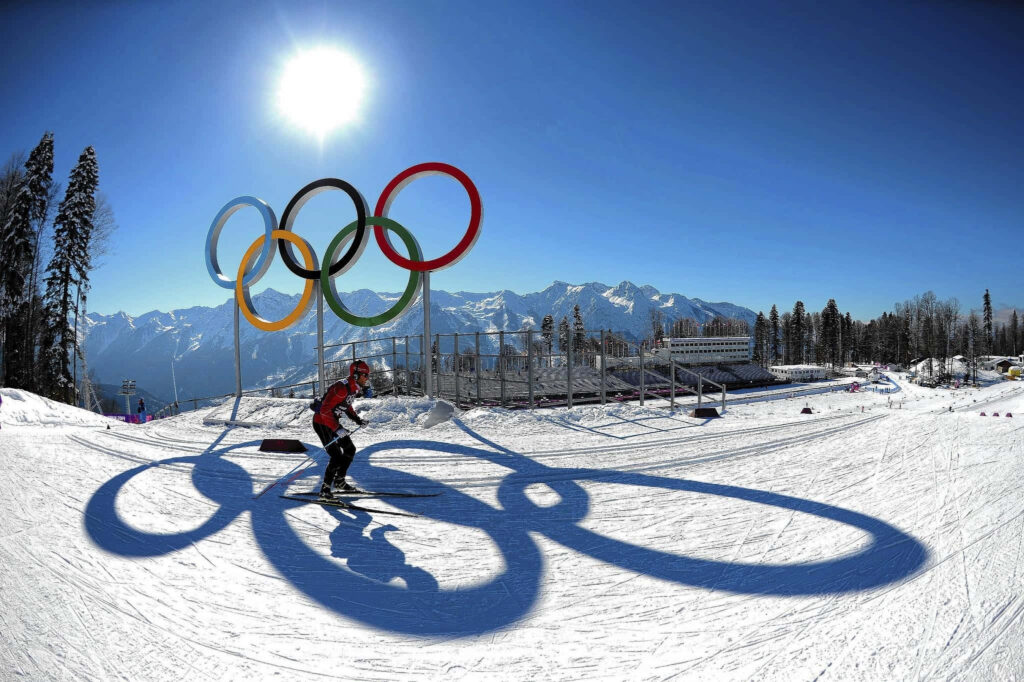 Snowboarder Gliding Under Sun with Olympic Rings - Winter Wallpaper