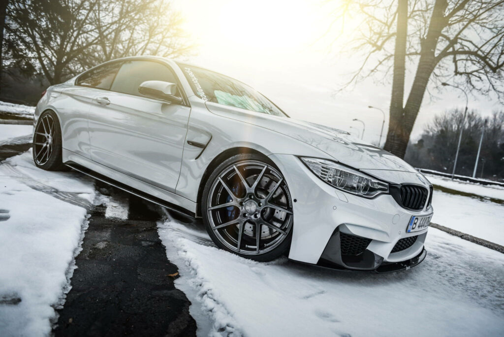 Breathtaking Winter Drive: Captivating White BMW M4 Parked on Snowy Landscape, Bathed in Sunlight Wallpaper