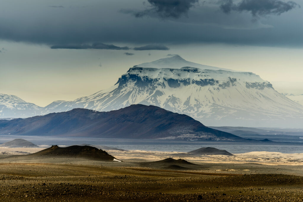 Snowy mountain with dramatic clouds and rugged earthy landscape wallpaper background serene