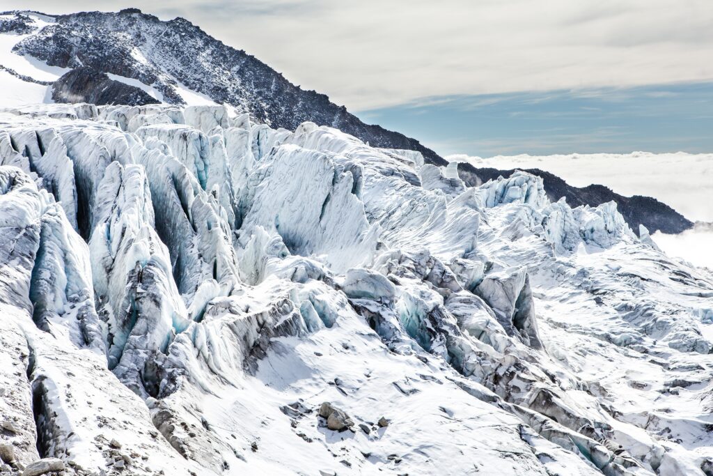 Snowy rugged mountain peaks with jagged stones in crisp blue high altitude winter landscape Wallpaper