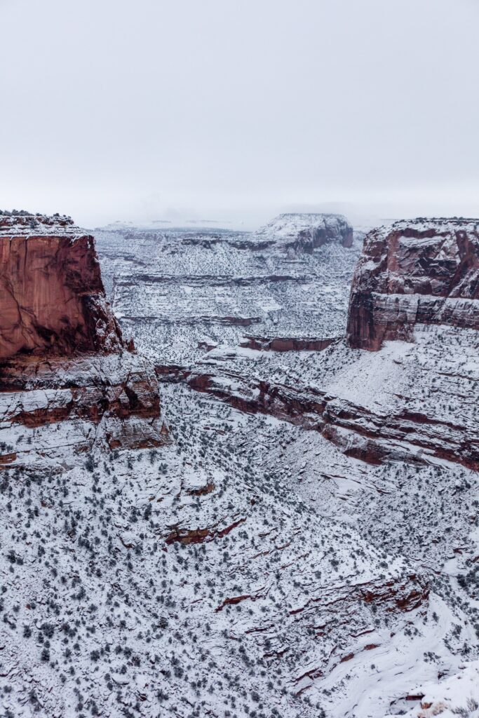 Snowy red rock cliffs under cloudy sky serene winter landscape wallpaper background