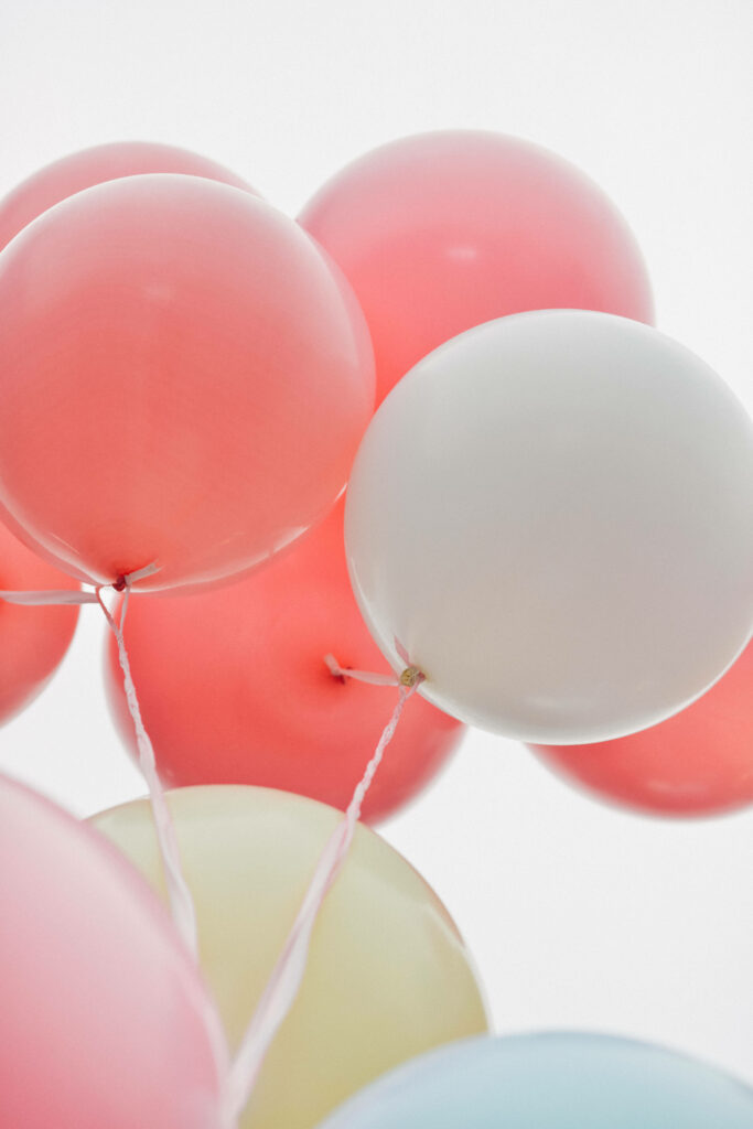 Soft pastel balloons floating gently on white background creating cheerful wallpaper design