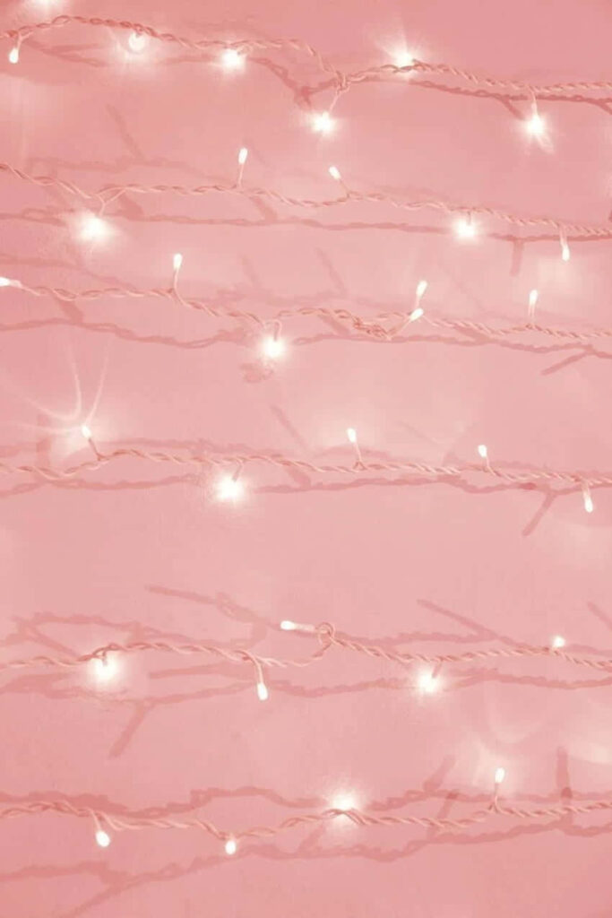Soft white string lights glowing on smooth pink background creating cozy whimsical wallpaper