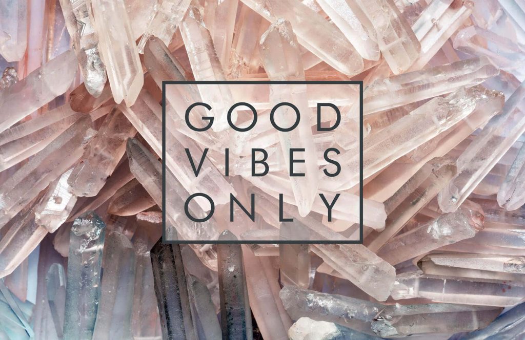 Soft-toned quartz crystal points with black framed Good Vibes Only text modern wallpaper background