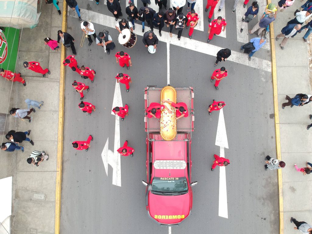 Aerial view of firefighter funeral procession with gold casket red rescue truck and marching band Wallpaper