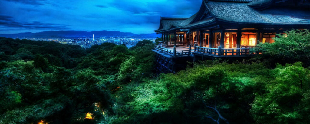 Kiyomizu-dera Temple at night with wooden stage lush forest and glowing Kyoto Tower skyline background Wallpaper