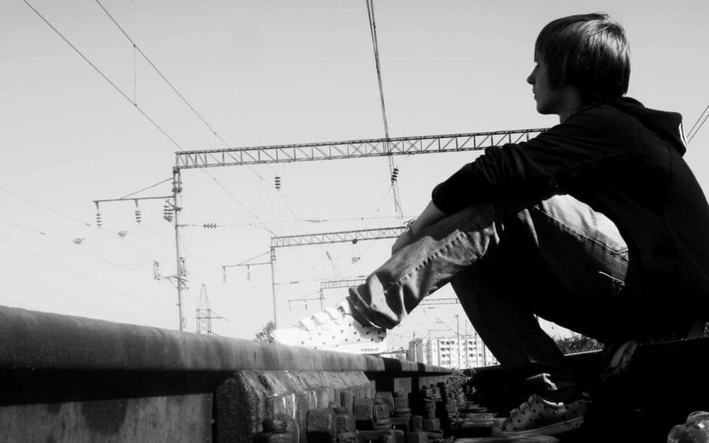 Solitary Boy on Train Rails: A Mood of Introspection in B&W Wallpaper
