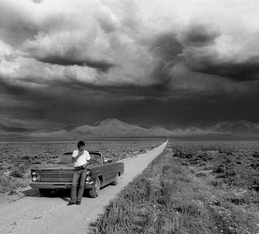 Solitary Figure & Classic Car: Introspective Black-and-White Wallpaper
