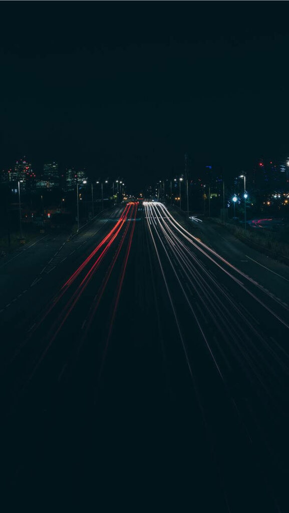 Lonely Night Drive: Dark Highway Illuminated by Red and White Trail Lights Wallpaper