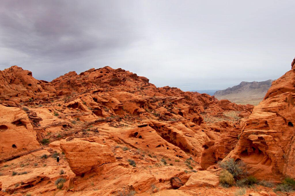 Silhouetted man in red rock canyon under cloudy sky capturing vast nature beauty wallpaper
