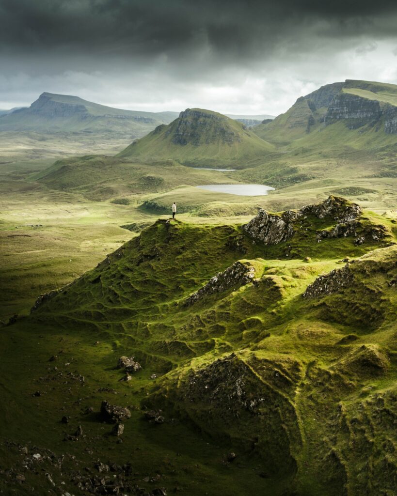 Solitary man on green hills overlooking rugged landscape near Portree under moody skies wallpaper