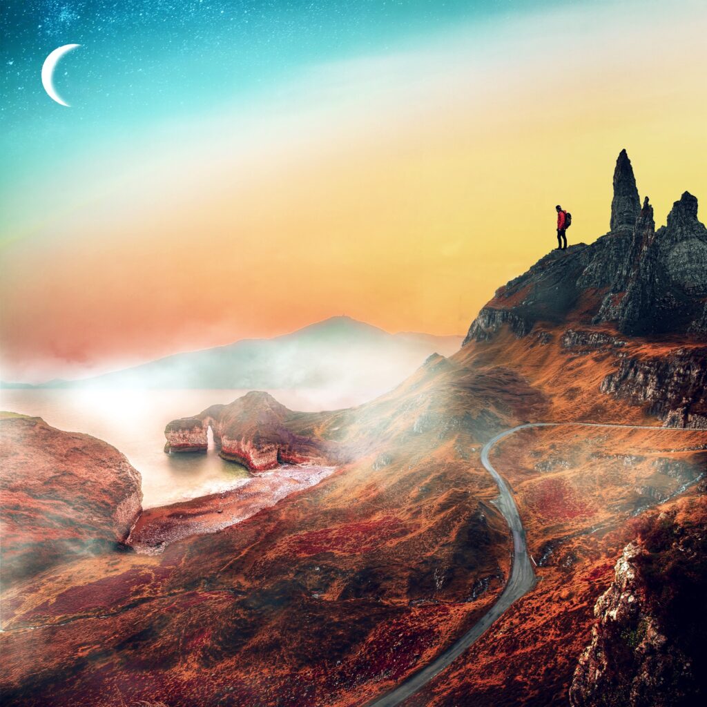 Man atop rugged mountain gazing over winding path under vibrant orange teal sky with crescent moon Wallpaper