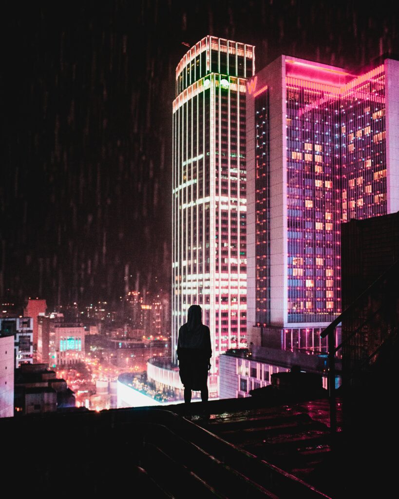 Solitary Silhouette on Rooftop: Neon Cityscape Wallpaper