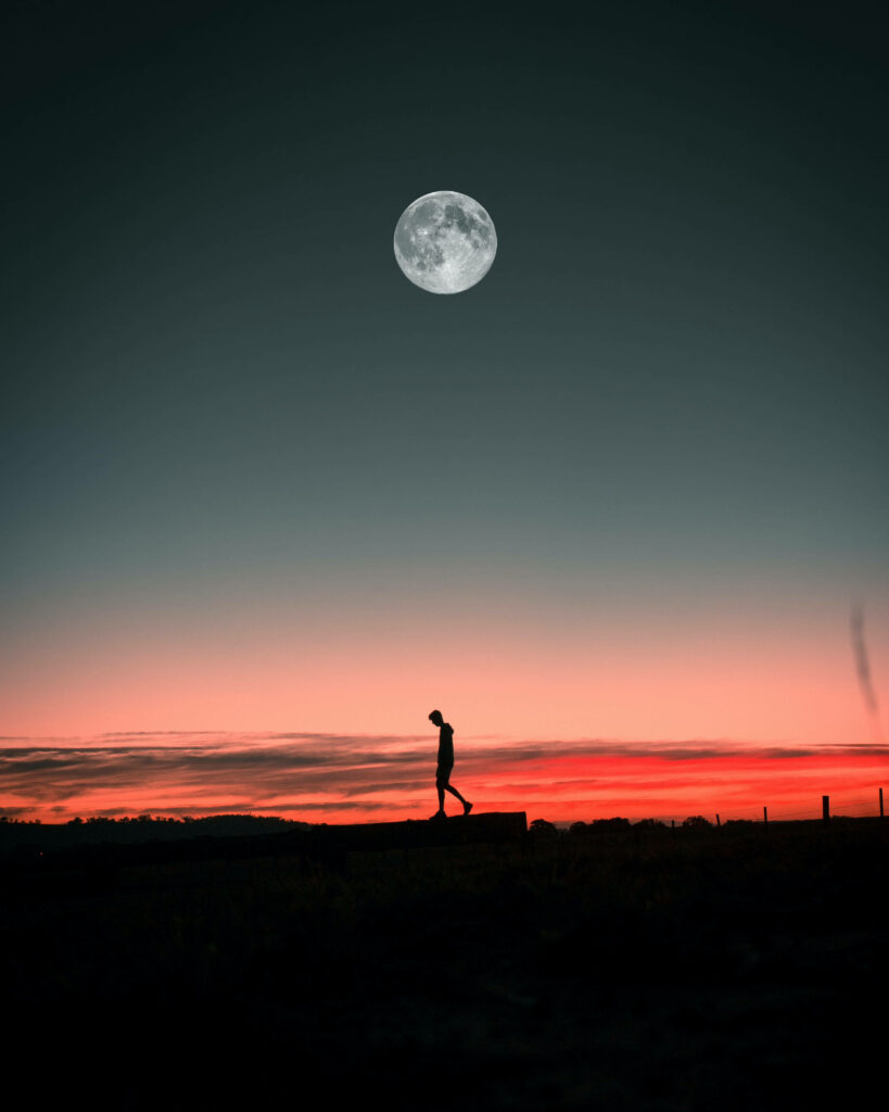 The Serene Journey: Tranquil Moonlit Ambience with a Solitary Boy Strolling through Open Landscape Wallpaper