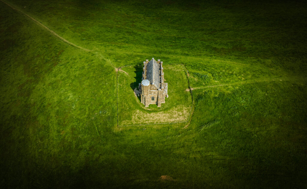 Aerial view of solitary stone house in lush green field with intersecting grassy paths rural landscape Wallpaper
