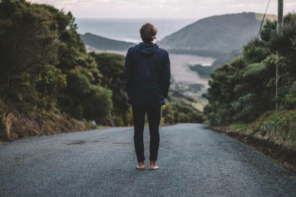 Isolated Desolation: The Loneliness of a Shoeless Man amidst Nature's Embrace Wallpaper