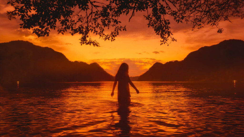 Solitude at Sunset: Captivating Alone Girl by the Lake - Beautiful Orange-toned Desktop Wallpaper