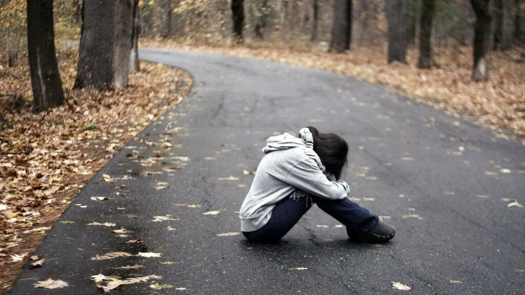 Lonely Roads: A QHD Wallpaper of a Sad Girl Sitting in the Grip of Depression