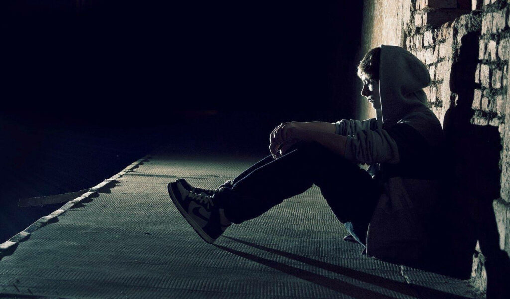 Solitude atop skyscrapers: A melancholic  background photo of a lone boy in a hoodie. Wallpaper