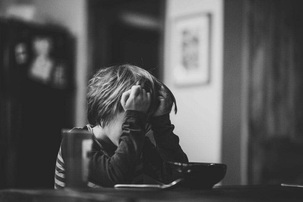 Somber Child Portrait: Black and White Image of Introspection Wallpaper
