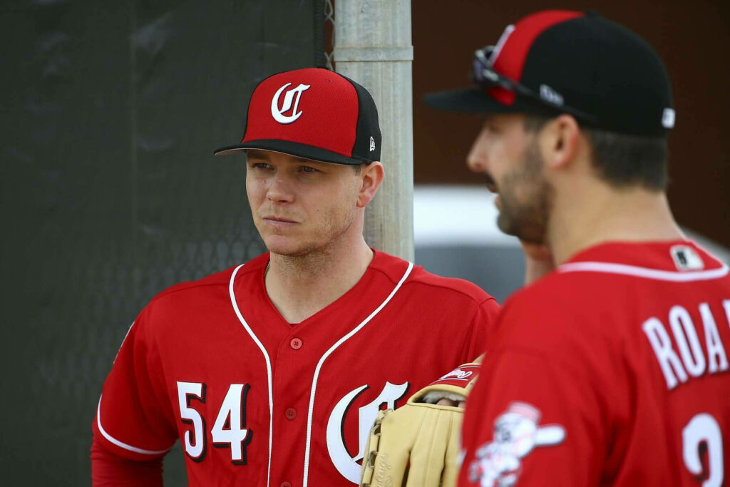 Sonny Gray in red Cincinnati Reds uniform number 54 focused during sunny baseball practice Wallpaper