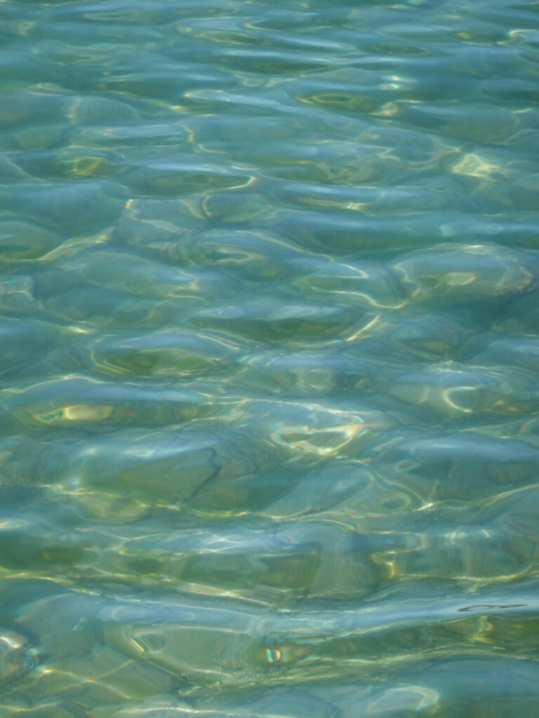 Soothing wallpaper with gentle blue green water waves and shimmering sunlight reflections