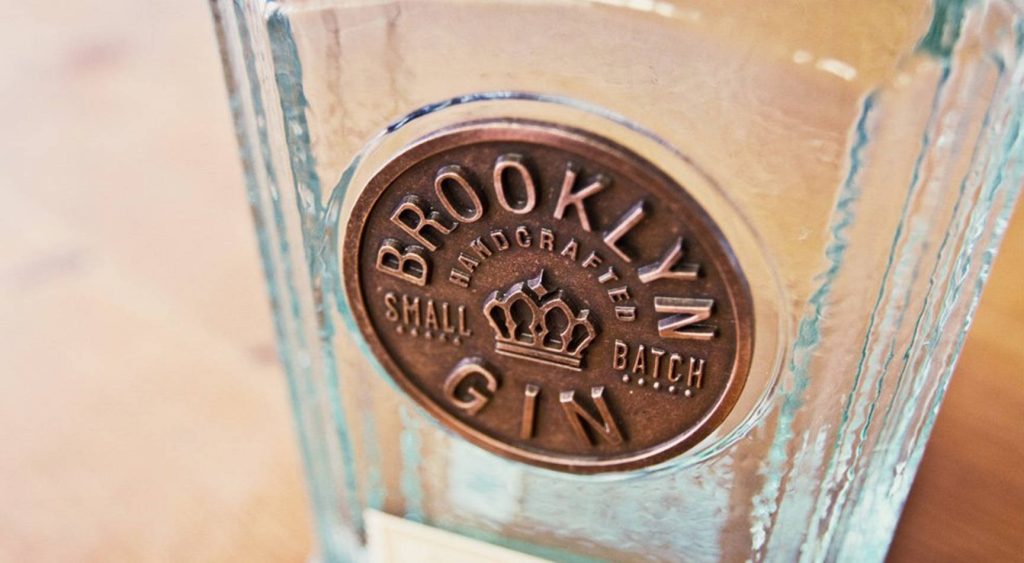 Close-up Brooklyn Gin bottle with bronze embossed label on warm blurred background wallpaper