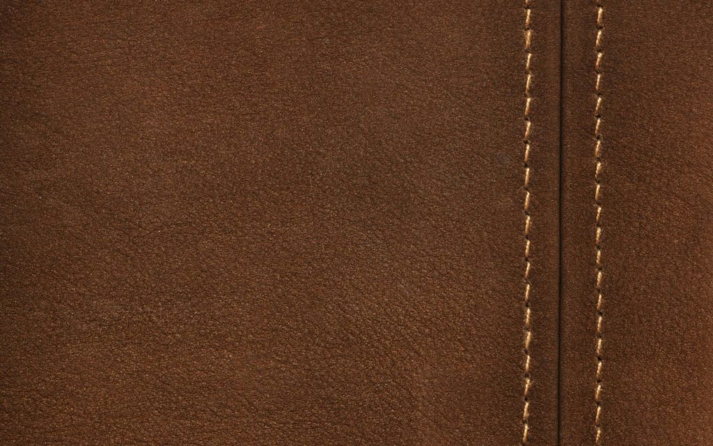 Closeup of brown leather wallpaper with matte texture and vertical stitched seam background