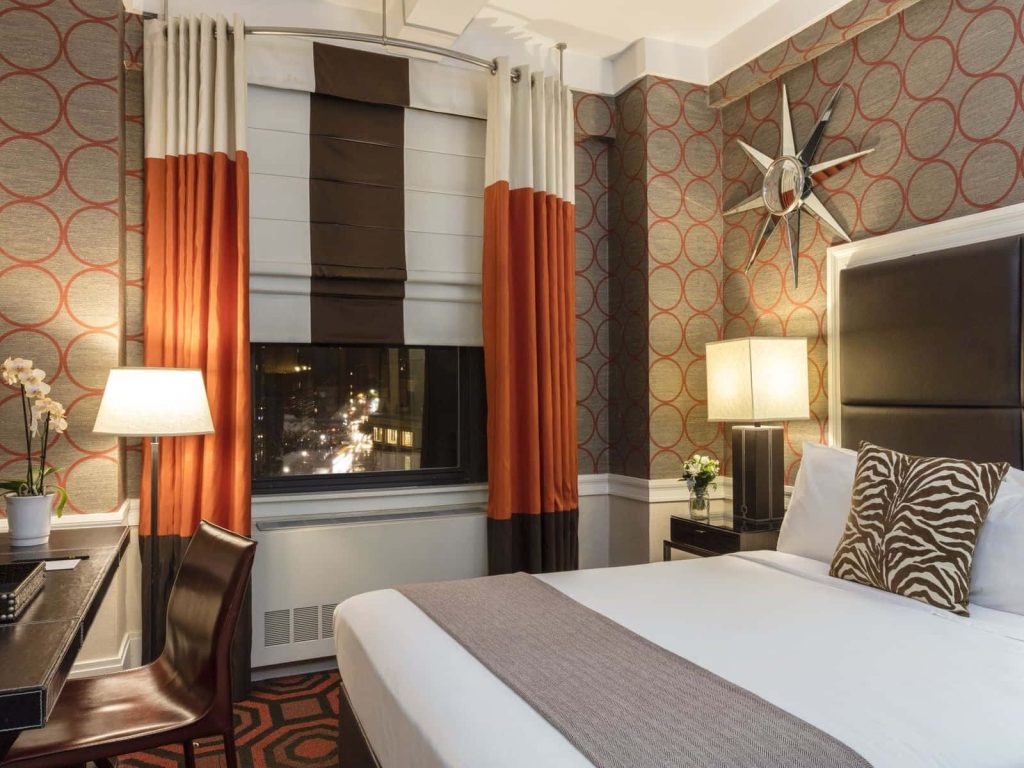 Elegant mid-century hotel room with circular wallpaper zebra print accents and starburst mirror