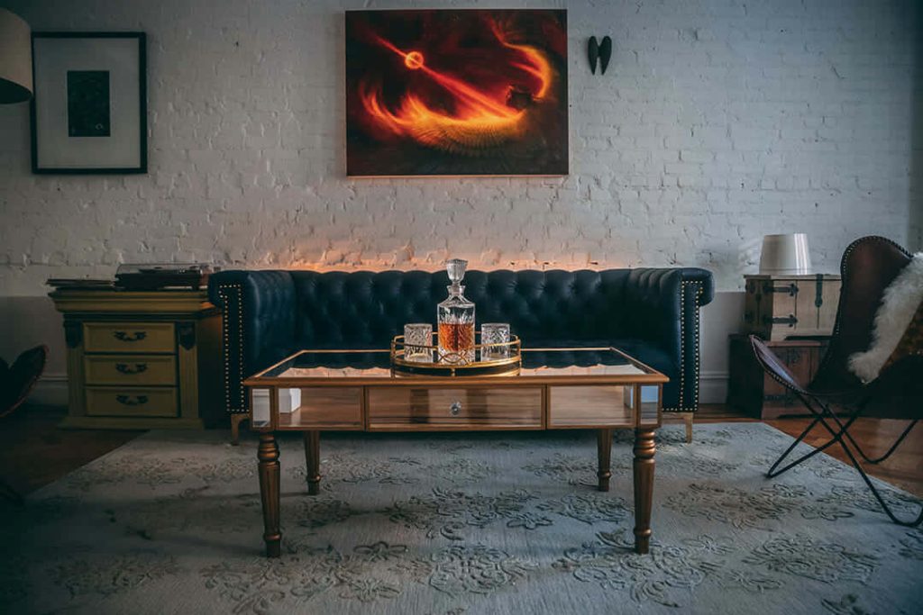 Moody elegant living room Zoom background navy sofa mirrored table whiskey set fire painting Wallpaper