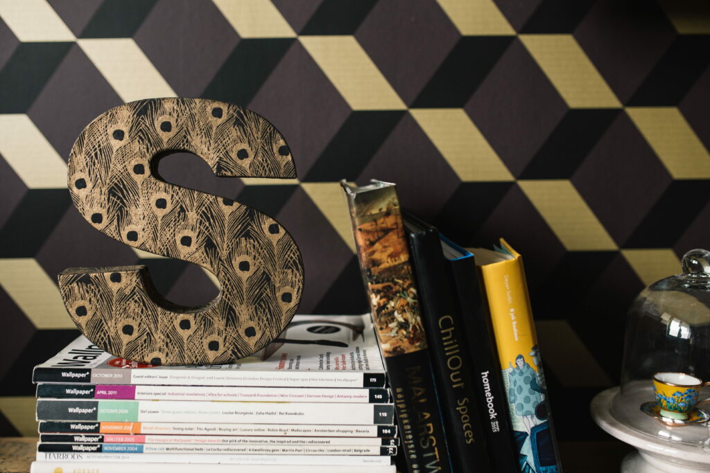 Sophisticated reading nook with peacock decorative S stacked magazines teacup geometric wallpaper