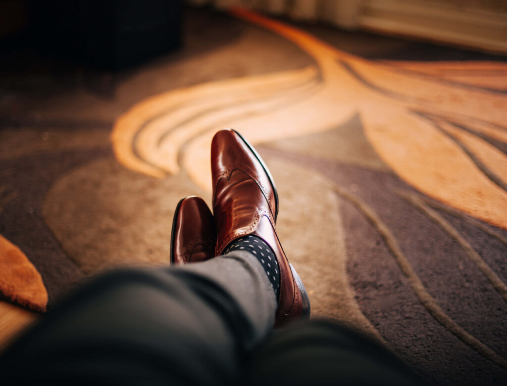 Refined Masculinity: Elegant Slacks and Polished Leather Shoes Complementing a Carpeted Setting - Stylish Male Feet Background Wallpaper