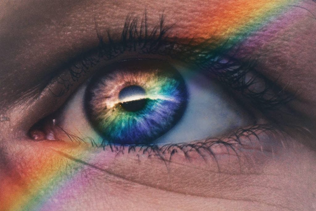 Close-up of a human eye with rainbow prism refracting vibrant moody tones artistic wallpaper background