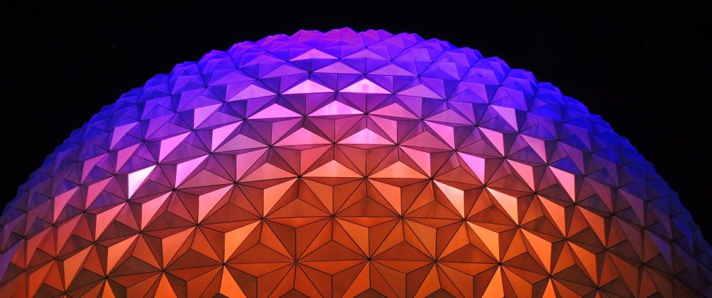 Spaceship Earth at Epcot glowing with amber and violet lights against night sky wallpaper background