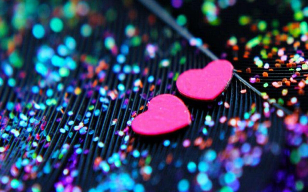 Vibrant glitter wallpaper with bright pink hearts on dark textured surface and colorful bokeh lights