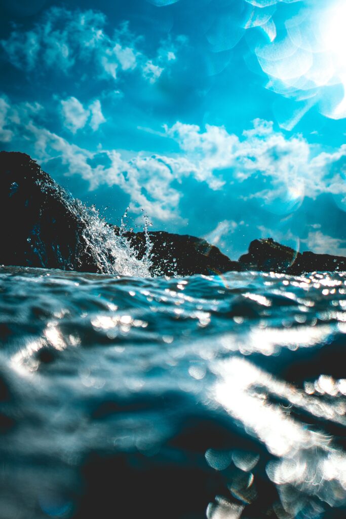 Vibrant ocean waves splashing under blue sky with soft glare and dreamy artistic blur background Wallpaper