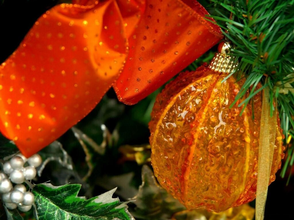 Vibrant Orange Christmas Ornament on Green Branch - Festive Wallpaper