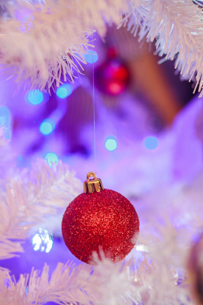 Sparkling Red Christmas Ornament on White Tree with Glowing Lights Wallpaper