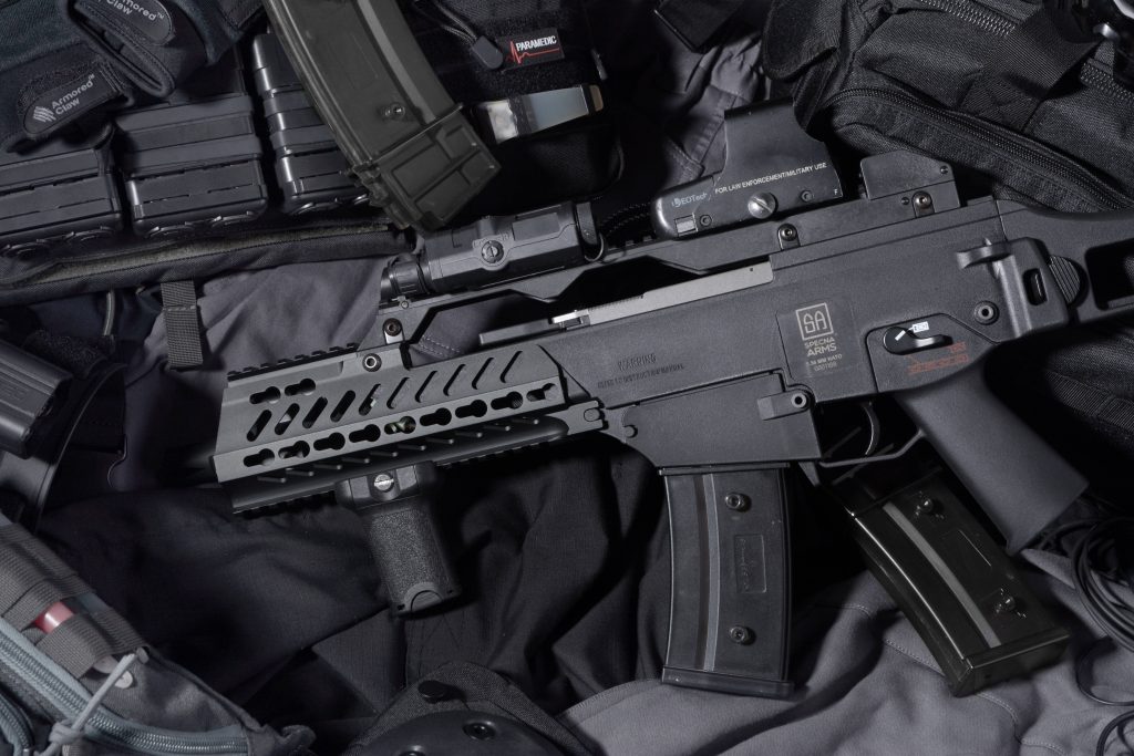 Black Specna Arms airsoft rifle with EOTech optic and tactical gear in high-contrast lighting Wallpaper