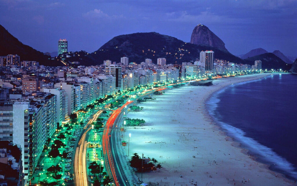 The Enchanting Glow of Copacabana Beach at Night: A Majestic Cityscape with Luminous Skyscrapers Wallpaper