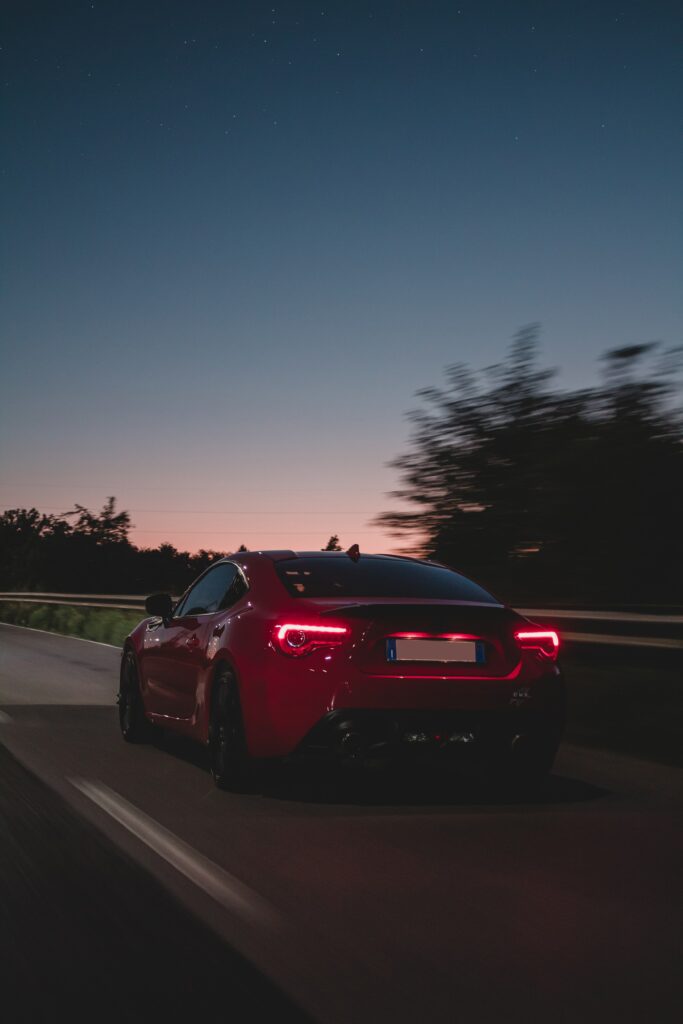 Dynamic Red Car Wallpaper: Speeding Down an Open Road at Dusk