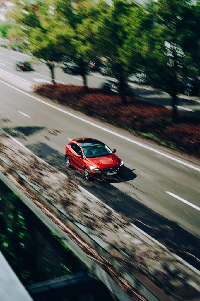 Dynamic Red Volvo Wallpaper: Speeding Through Lush Greenery