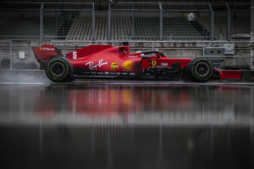 Sebastian Vettel Ferrari F1 car number 5 racing on rain-soaked track with reflection wallpaper