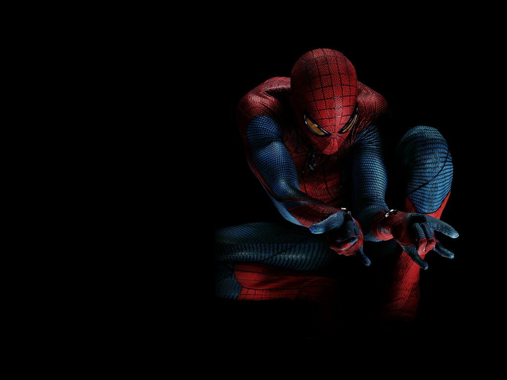 Spiderman in red and blue suit crouched ready to shoot webs on dark Marvel movie wallpaper