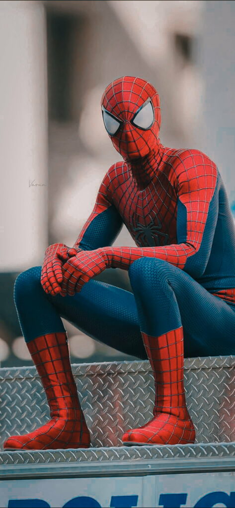 Spiderman Andrew in red-blue suit perched thoughtfully on metal surface HD wallpaper background
