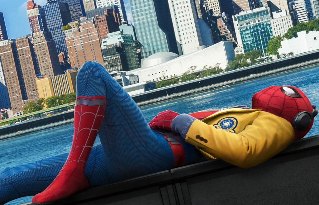 Spiderman in suit and yellow jacket relaxing on rooftop with city skyline and river HD wallpaper